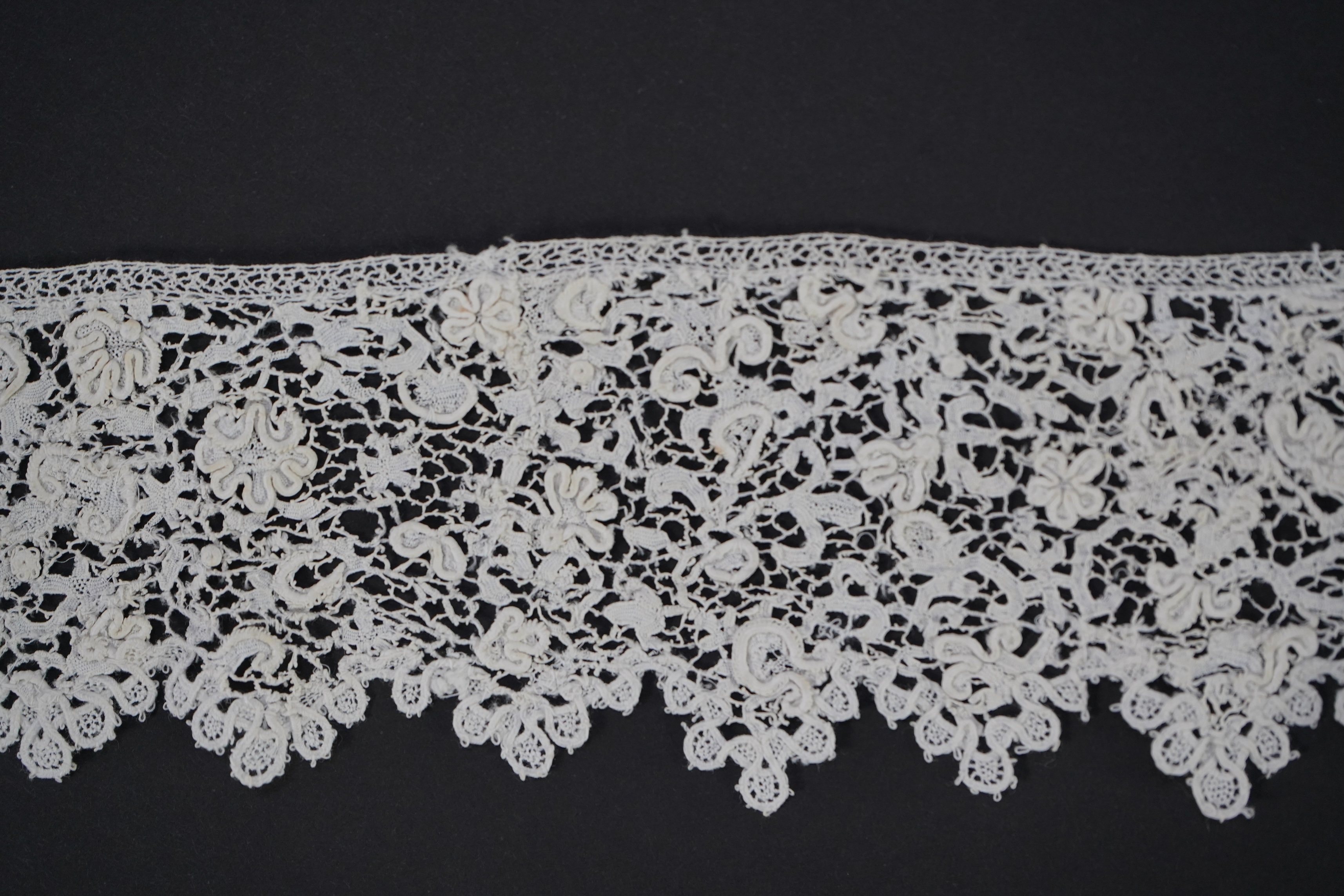 A late 17th century wide flounce of Point de France needle lace, together with a narrower flounce, both with raised elements of the design in the style of Point de Rose, but less so. This lace was very popular with the F